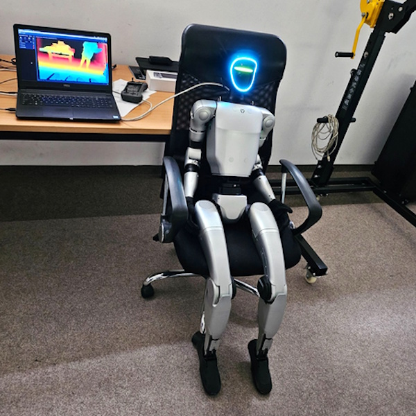 Robot humanoidalny siedzący na fotelu, podłączony do laptopa